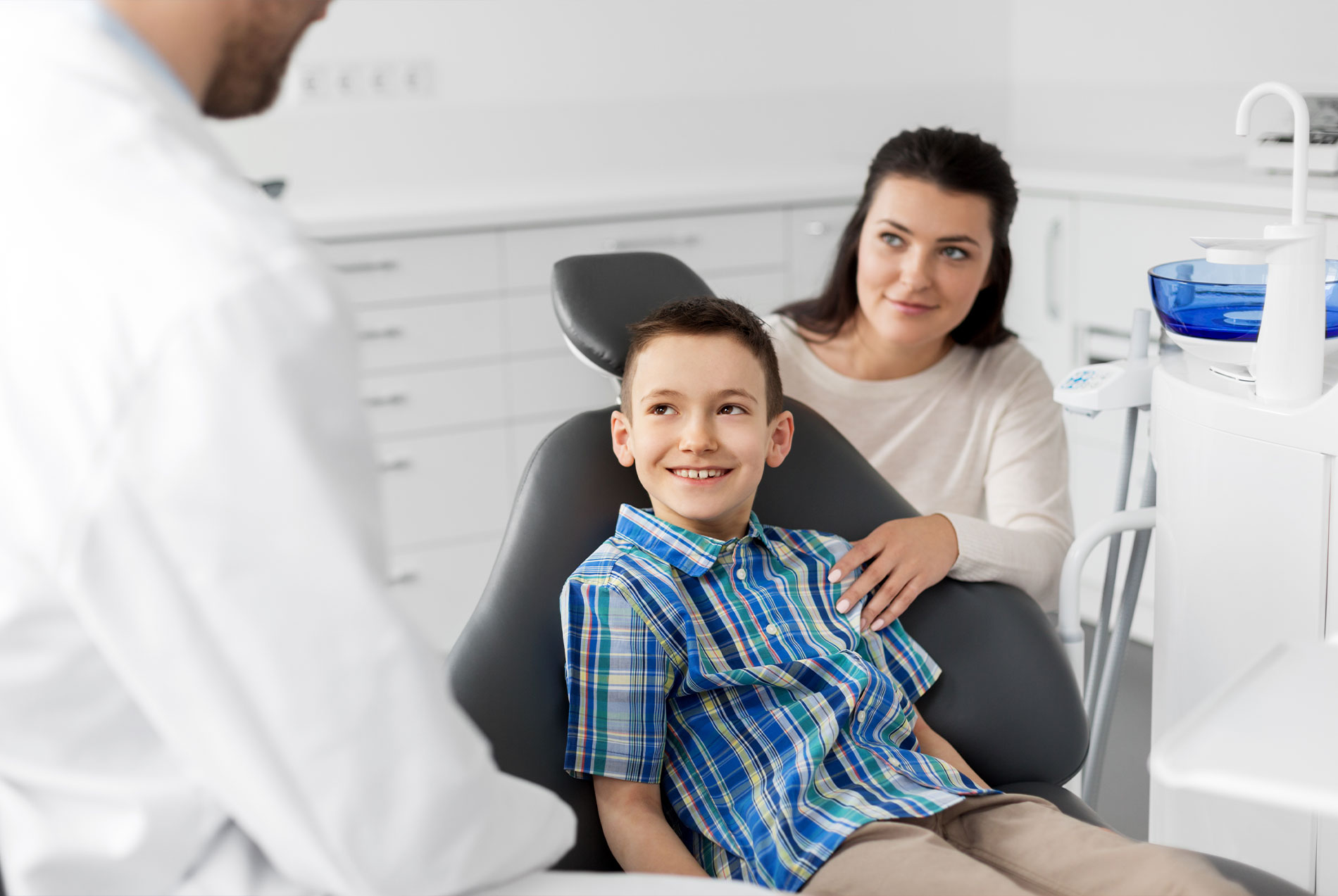 The image shows a dental office setting with a dentist, a patient, and a chair for dental procedures.
